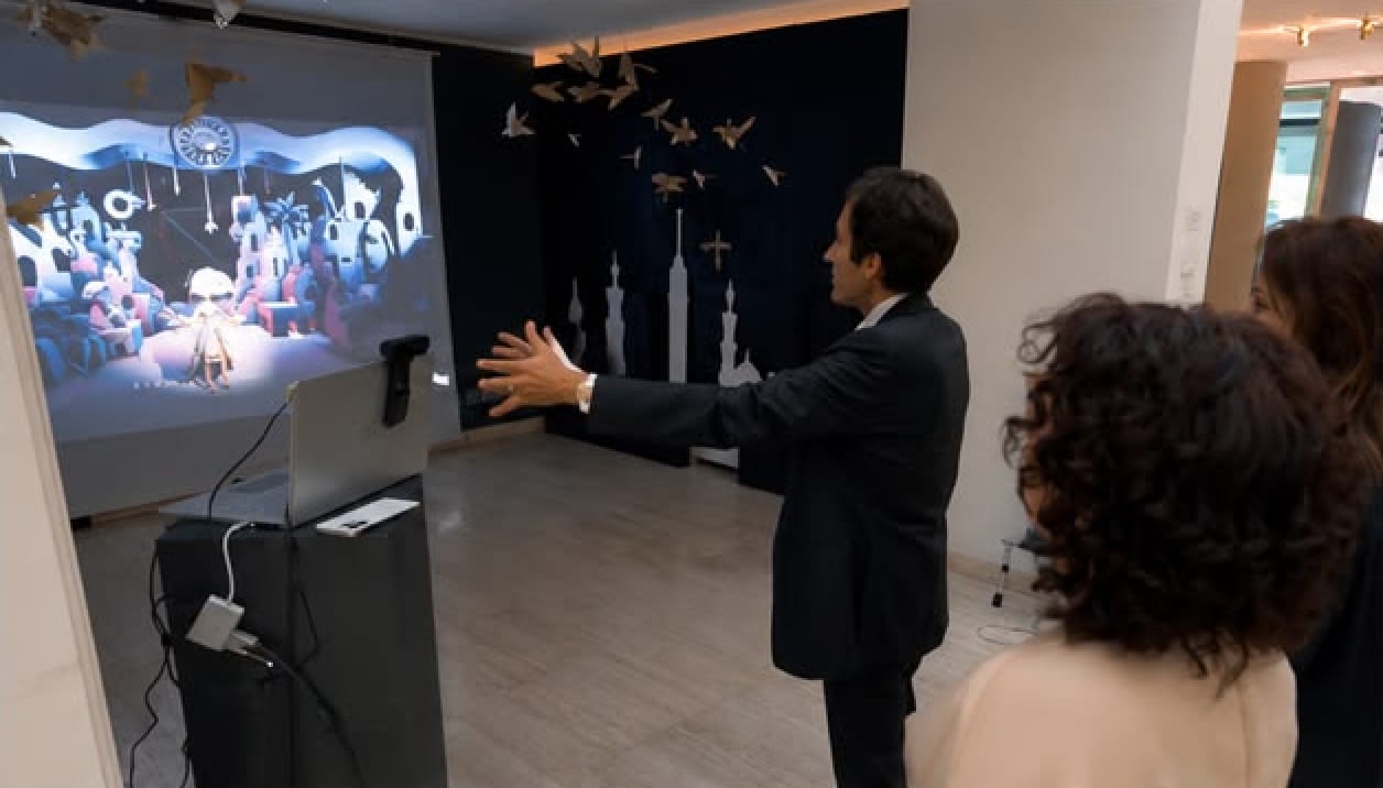 A visitor in a suit reaches toward the CLAP FOR ME projection while two women watch beside him