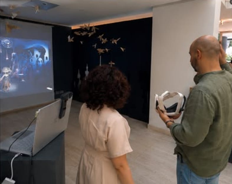A woman watches the projection while a man holds the CLAP FOR ME headset