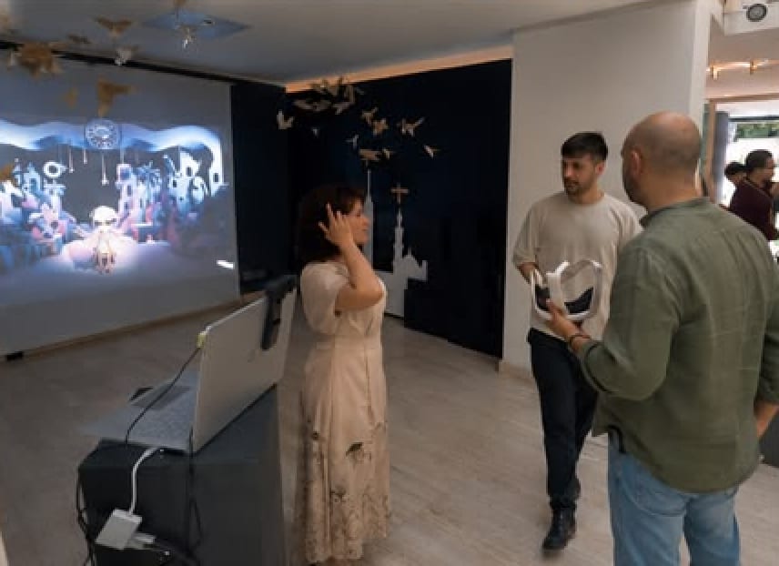 Three visitors gathered in front of the CLAP FOR ME projection, one adjusting the headset
